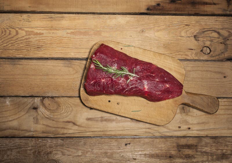 Raw Beef Steak on a Cutting Board with Rosemary and Spices. Stock Photo