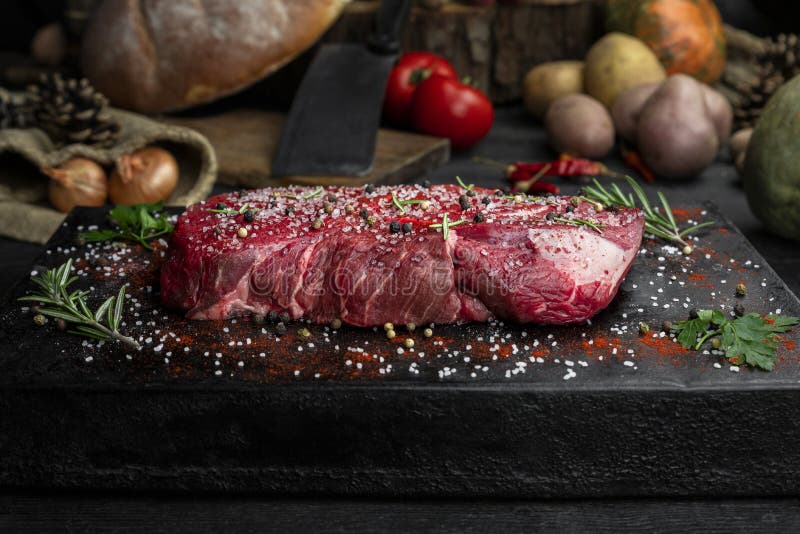 Raw Beef Steak Seasoned with Salt, Pepper and Fresh Hearbs Stock Photo
