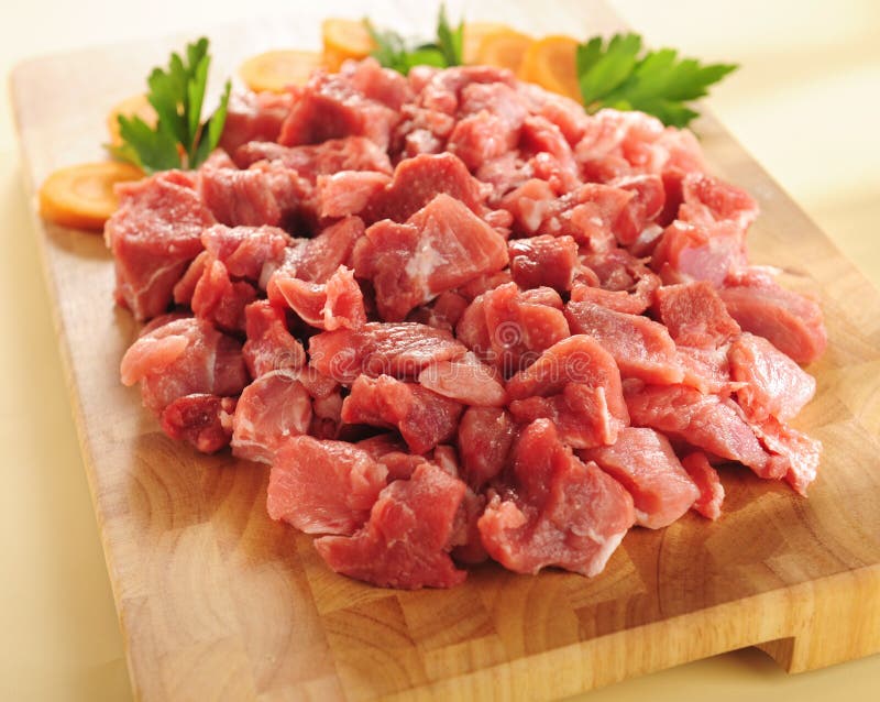 Raw spezzatino di carne su un tagliere di legno.