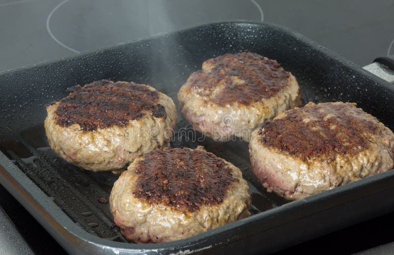 Raw Burgers, Beef in a Frying Pan on Cooking Surface in Kitchen Stock