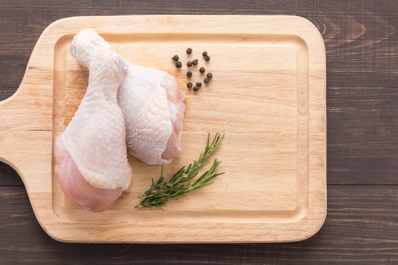 Raw Chicken Drumsticks on Cutting Board on Wooden Background Stock