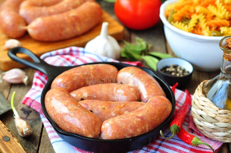 Raw Chicken Sausages with Vegetables on a Frying Pan Stock Photo