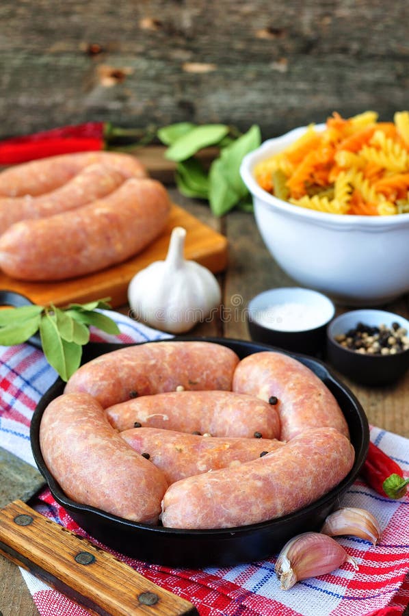 Raw Chicken Sausages with Vegetables on a Frying Pan Stock Photo