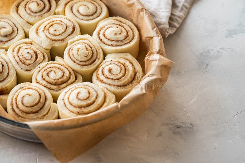 Raw Cinnamon Rolls in Baking Plate on Kitchen Table. Copy Space. Stock