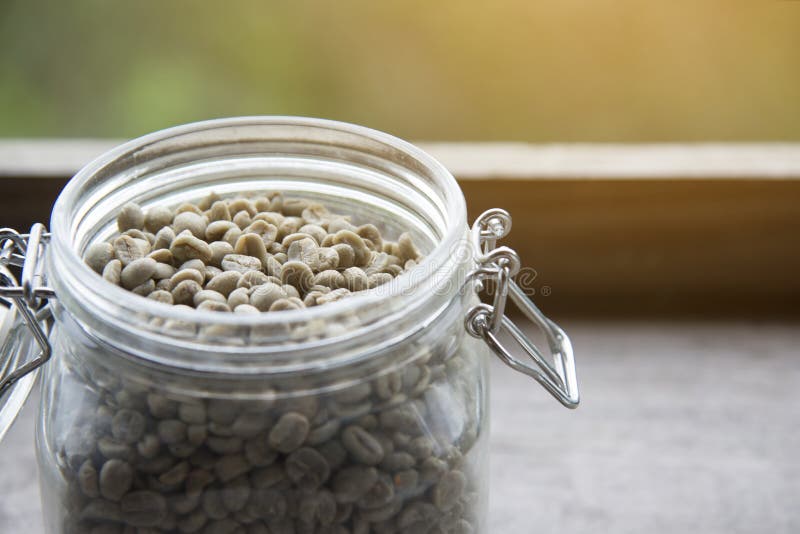 Raw coffee beans,unroasted coffee beans in glass jar on wooden table royalty free stock images Raw coffee beans,unroasted coffee beans in glass jar on wooden table royalty free stock images