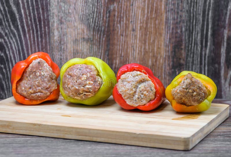 Raw Colored Bell Peppers Stuffed with Meat on a Cutting Board Stock