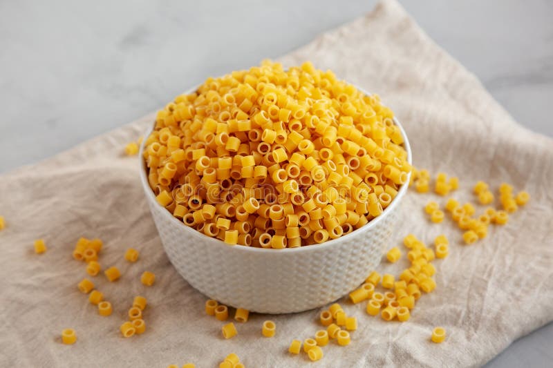 Raw Ditalini Pasta in a Bowl on a Gray Background, Side View Stock