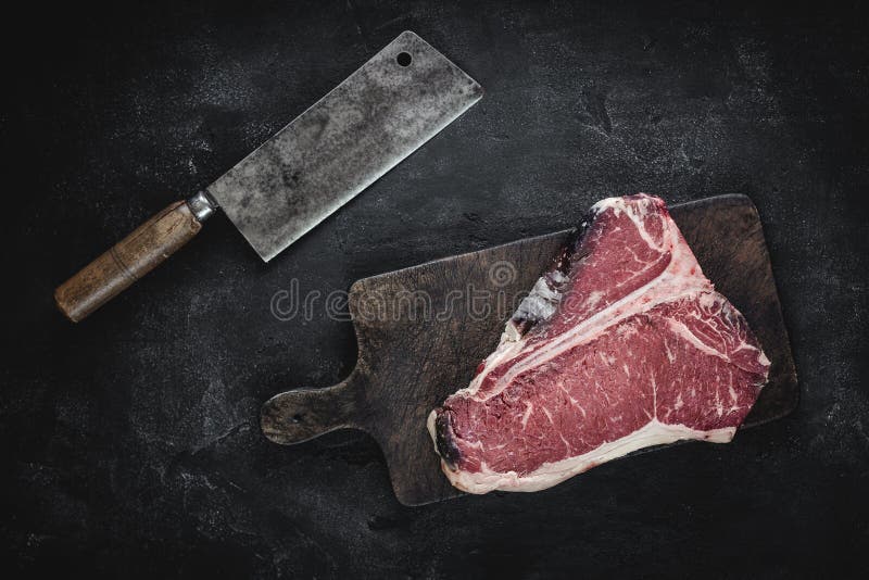 Raw Dry Aged T-bone Steak on Vintage Chopping Board with Meat Cleaver. 