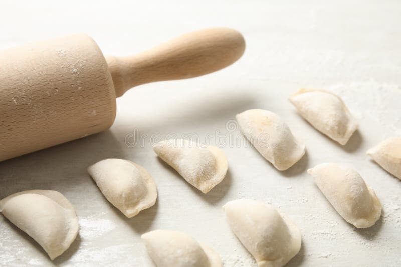 Raw Dumplings and Rolling Pin on Light Background, Closeup. Process