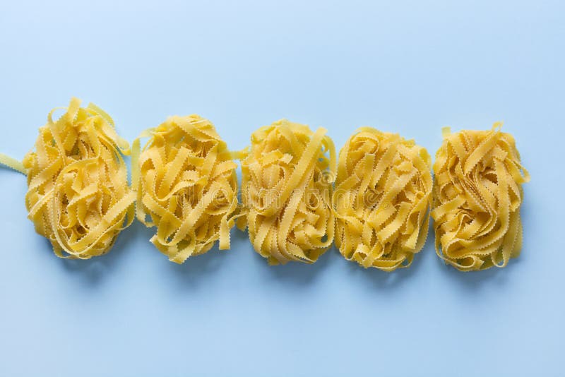 Raw Egg Pasta Shape Reginella Rolled Up by Portion on Blue. View from