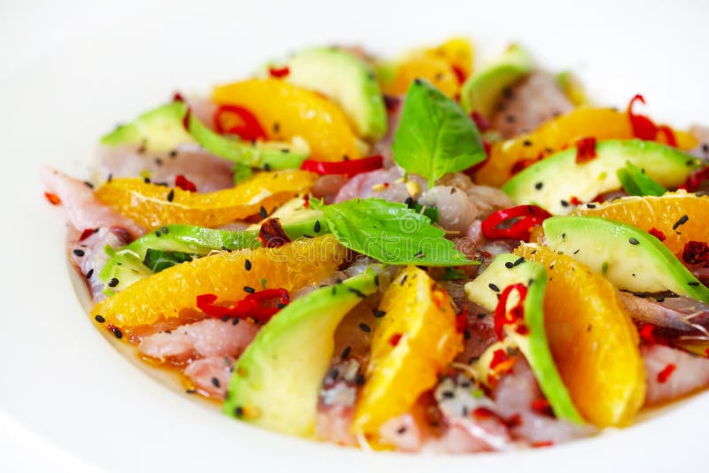 Raw fish salad carpaccio with avocado and orange slices
