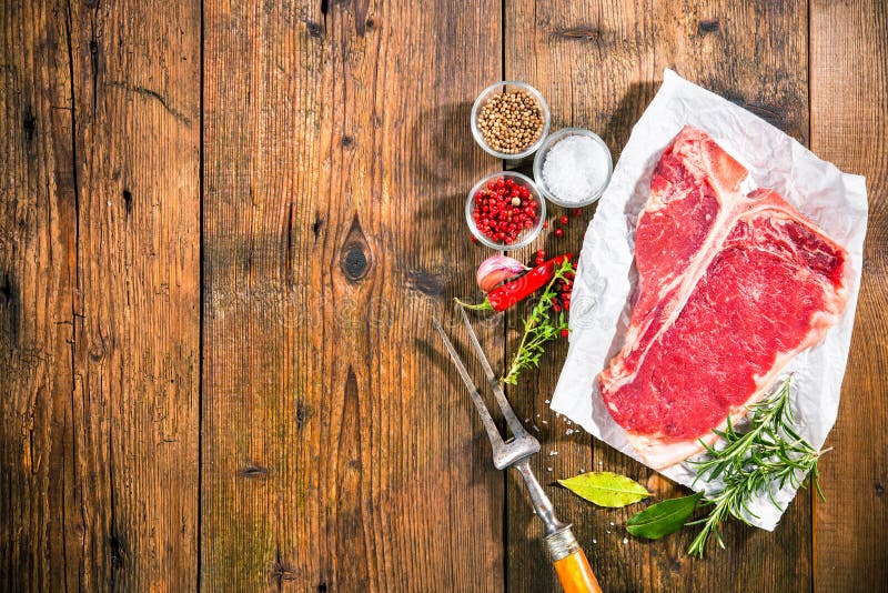 Raw Fresh Meat TBone Steak with Salt and Pepper on Wooden Background