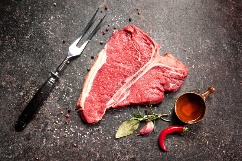Raw Fresh Meat TBone Steak with Salt and Pepper on Wooden Background