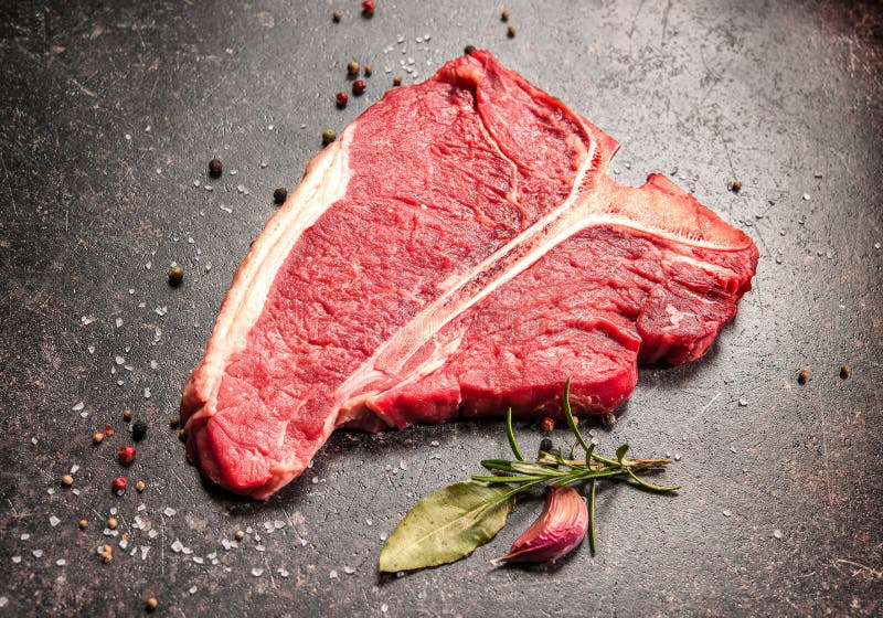 Raw Fresh Meat TBone Steak with Salt and Pepper on Wooden Background