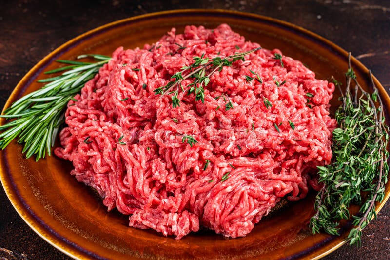Raw Ground Beef or Veal Meat on a Rustic Plate with Herbs. Dark