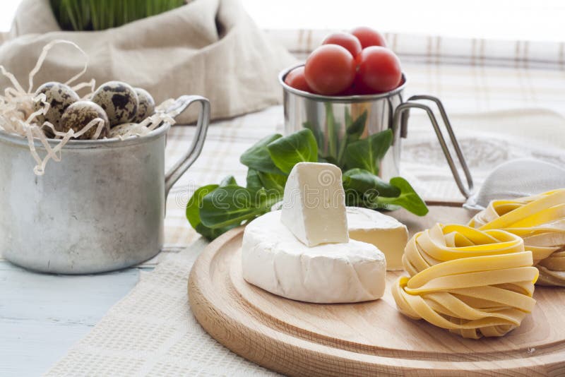 Raw homemade pasta, quail easter eggs in a aluminum cup, green lettuce, tomatoes and flour on wooden table royalty free stock images Raw homemade pasta, quail easter eggs in a aluminum cup, green lettuce, tomatoes and flour on wooden table royalty free stock images