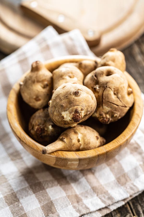Raw Jerusalem Artichoke. Topinambur Vegetable Root in a Wooden Bowl
