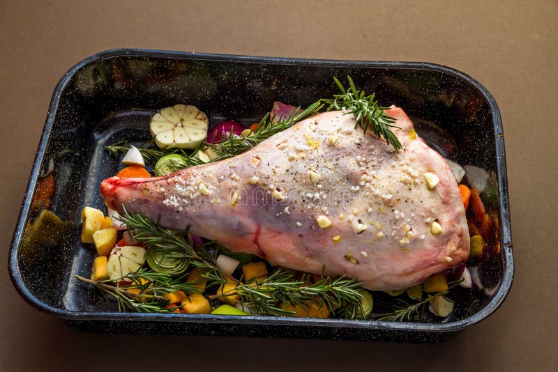 Raw Leg of lamb in roasting tray dressed with vegetables