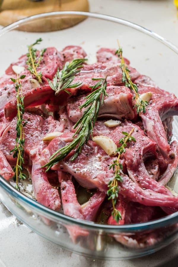 Raw Marinated Lamb Chops with Rosemary, Olive Oil and Garlic in Glass