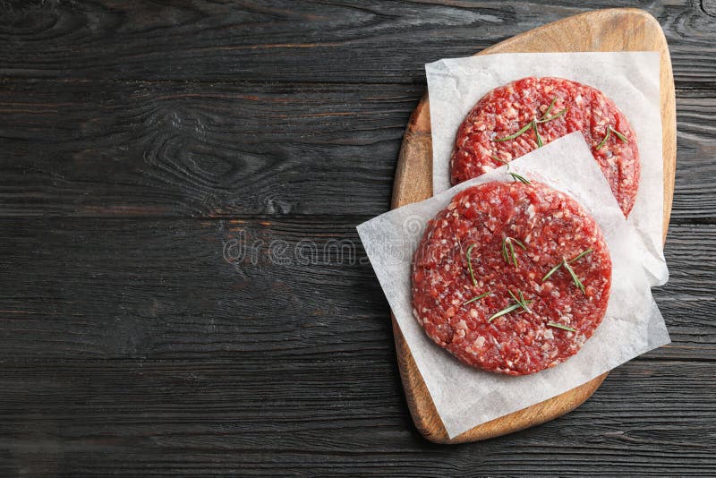 Raw meat cutlets for burger on wooden table, top view. Space for text