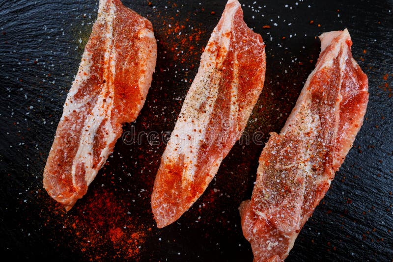 Raw meat on dark background. Raw pork steak with herbs, oil and spices. Cooking meat. royalty free stock photography Raw meat on dark background. Raw pork steak with herbs, oil and spices. Cooking meat. royalty free stock photography