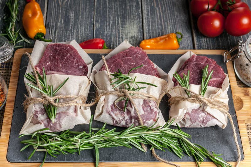 Raw Meat Steaks and Rosemary. Fresh Meat on a Cutting Board, Herbs and