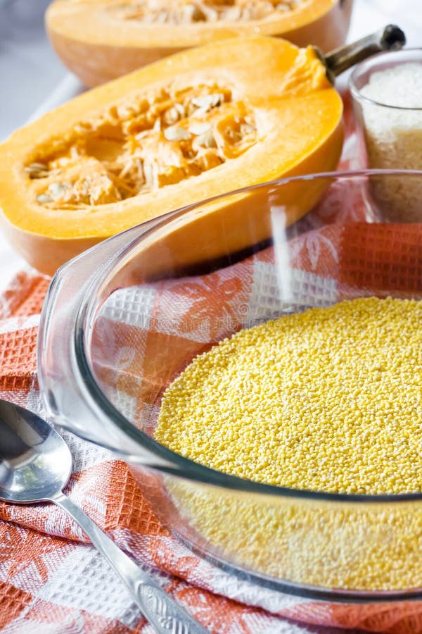 Raw millet in a glass pan in the process of preparing milk porridge with pumpkin and raisins stock photos Raw millet in a glass pan in the process of preparing milk porridge with pumpkin and raisins stock photos