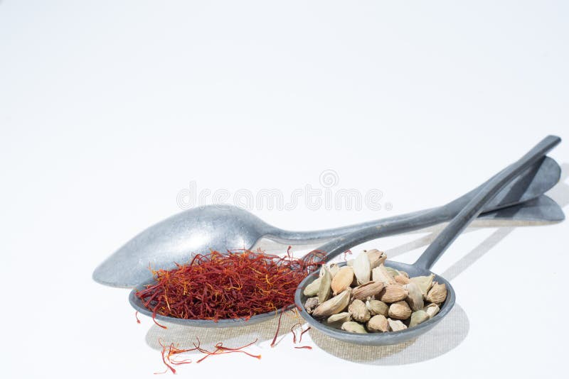 Raw Organic Red Saffron and Cardamom Spices in Old Tin Spoons on Stock