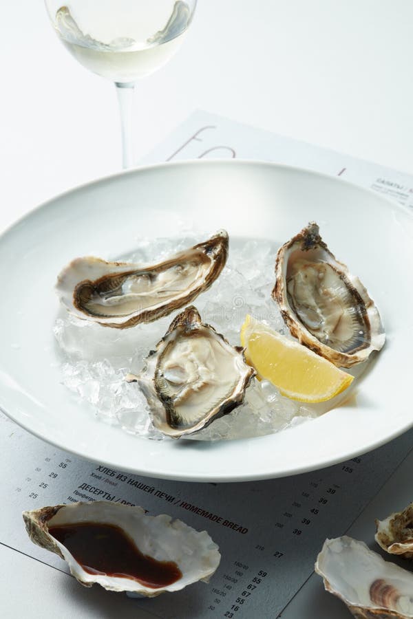 Raw Oysters served on the half shell over ice with lemon in the plate. Bivalve shell stock images, royalty-free photos and pictures
