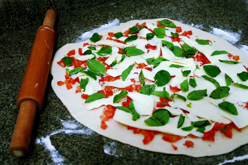 Raw Pizza Dough with Cheeses, Tomatoes and Basil Leaves. Pasta Roller