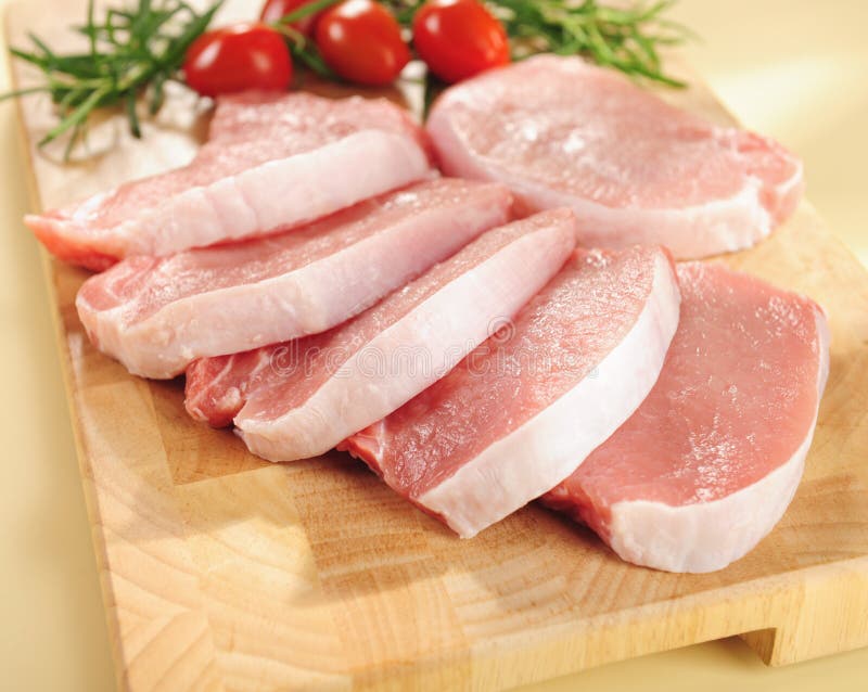 Raw pork chops. Arrangement on a cutting board.