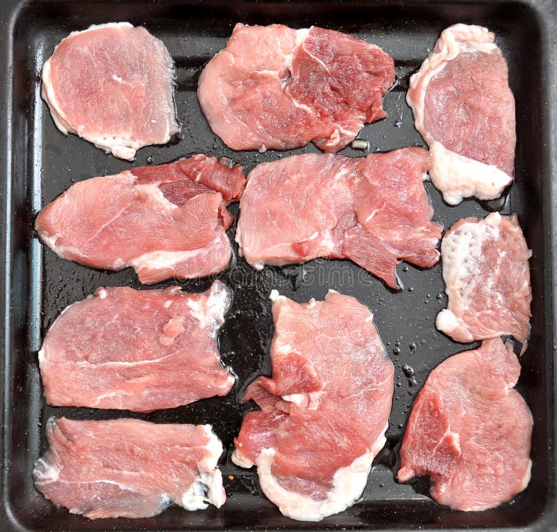 Raw Pork Chops on a Black Baking Tray. Process of Cooking Step by Step