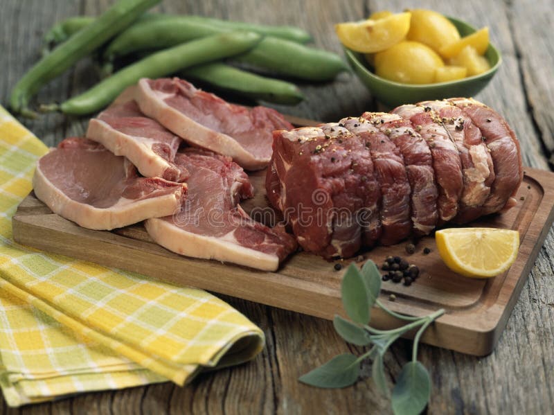 Raw pork chops and roast on a chopping board