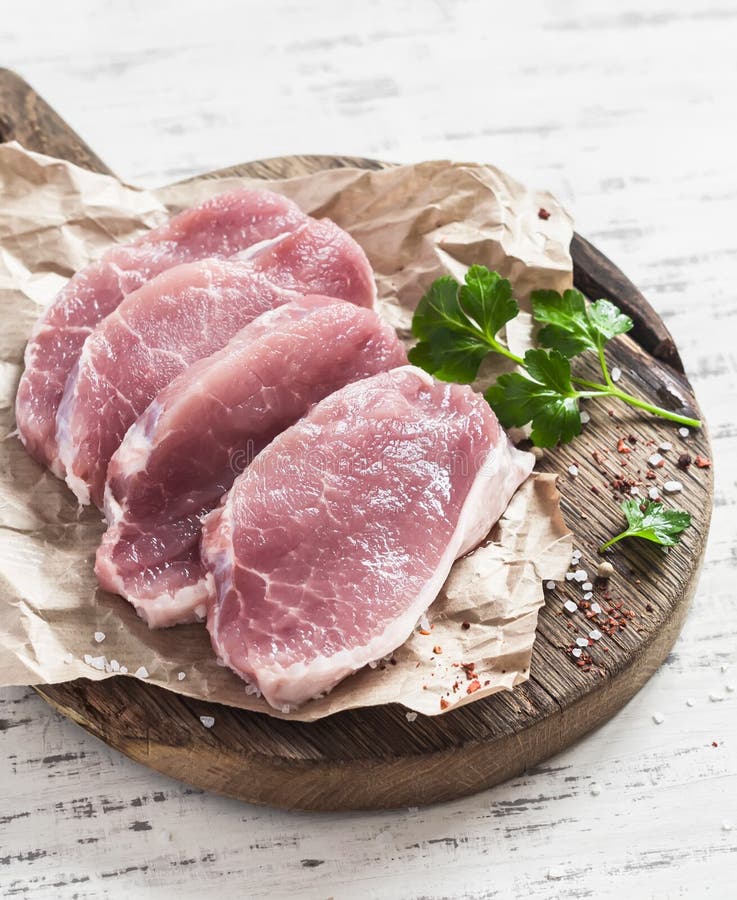 Raw pork chops on a wooden cutting board