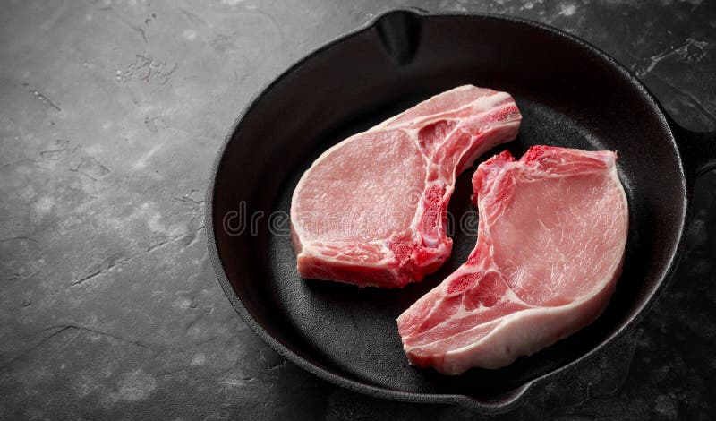 Raw Pork Loin chops in rustic skillet, pan. top view. background