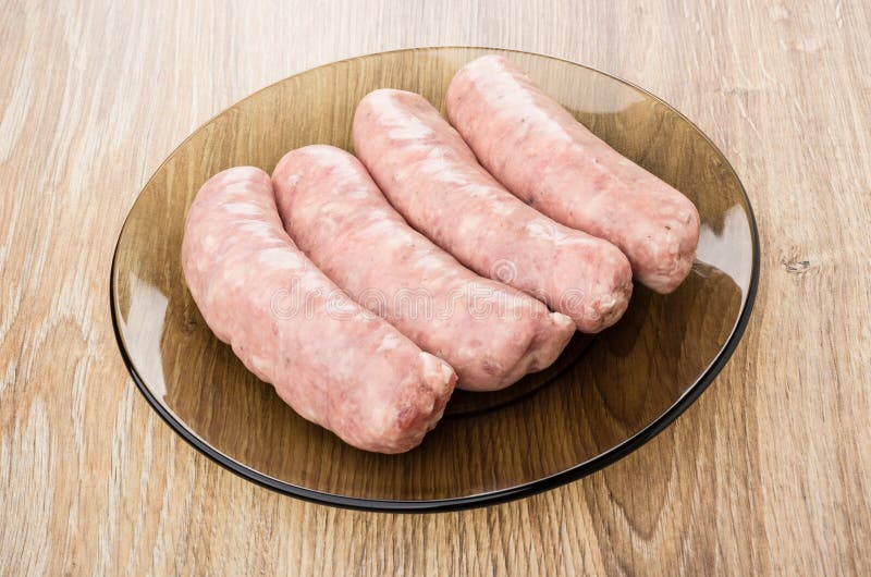 Raw Pork Sausages on Orange Plastic Cutting Board on White Stock Photo
