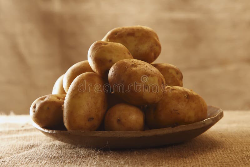 Raw potatoes on plate with burlap rustic