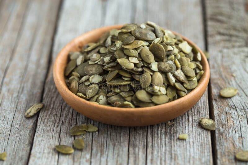 Raw Pumpkin seeds close up in wooden bowl stock photo Raw Pumpkin seeds close up in wooden bowl stock photo