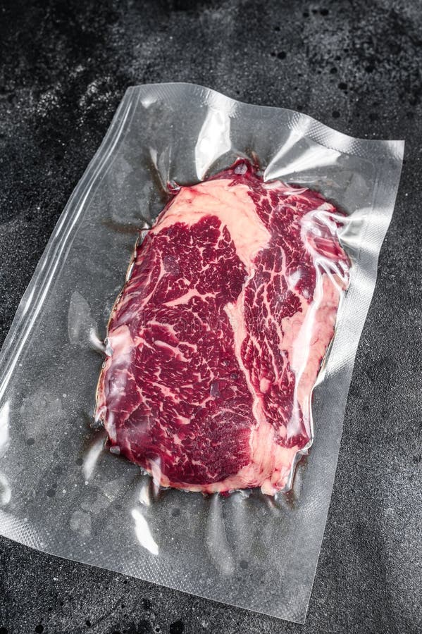 Raw Rib Eye Beef Meat Steak in Vacuum Packaging. Black Background Stock
