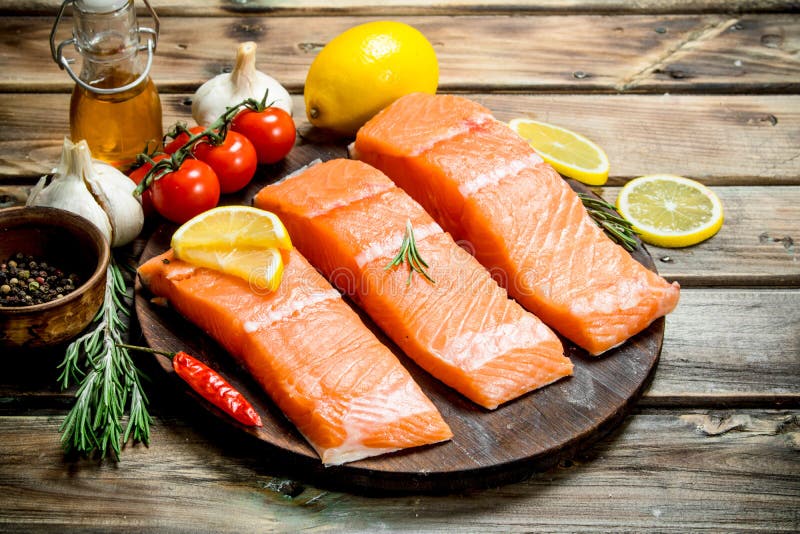 Raw salmon fish filet with lemon, tomatoes and herbs