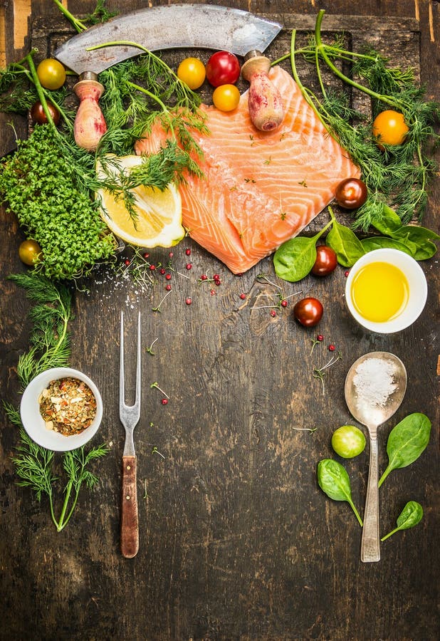 Raw salmon preparation for cooking on rustic wooden background with fresh ingredients , fork and spoon, top view