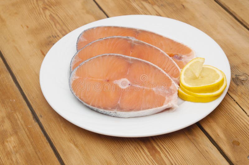 Raw salmon steak on white dish