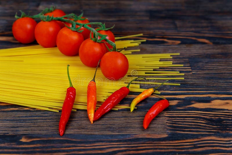 raw spaghetti bavette with tomatoes, pepper ingredients for cooking Italian pasta. Fresh vegetables and uncooked italian pasta on