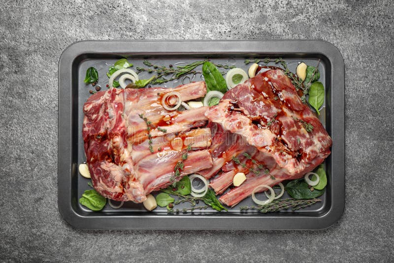Raw spare ribs with herbs and seasonings on grey table, top view stock photo Raw spare ribs with herbs and seasonings on grey table, top view stock photo