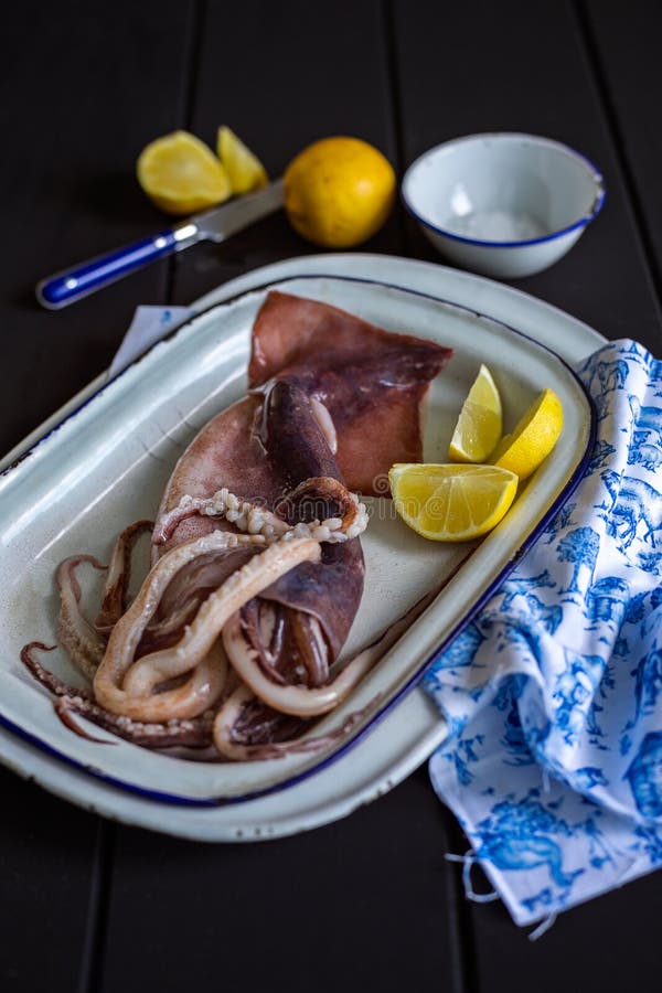 Raw squid with lemon wedges stock photo