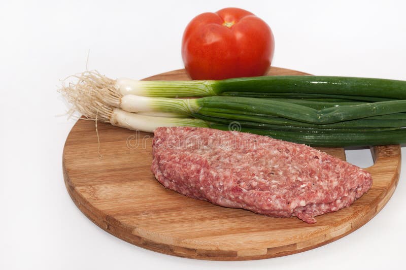 Raw Stuffed Hamburger on Wooden Board with Tomatoes and Onions Stock