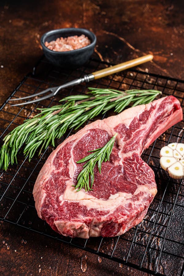 Raw Uncooked Dry Aged Beef Tomahawk or Rib Eye Steak. Dark Background