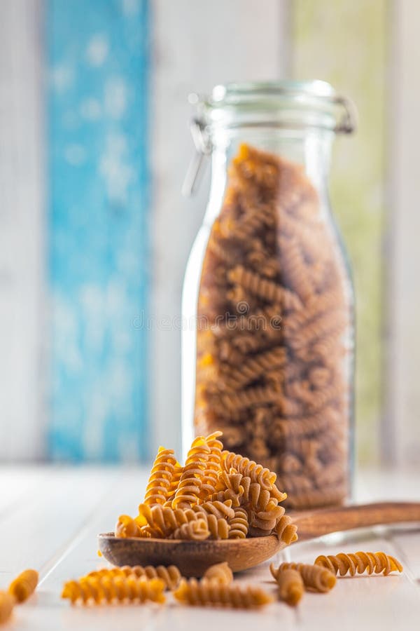 Raw whole grain fusilli pasta. Uncooked pasta on wooden spoon royalty free stock images