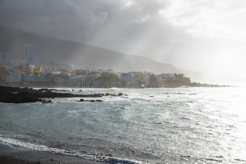 Rayons de soleil au-dessus du littoral avec des maisons pendant le coucher du soleil au blac image libre de droits Rayons de soleil au-dessus du littoral avec des maisons pendant le coucher du soleil au blac image libre de droits