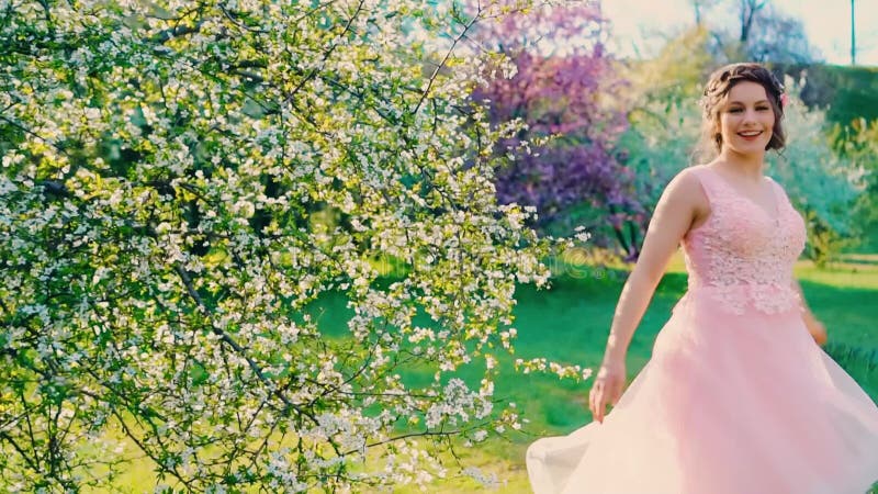 Rayons lumineux solaires. Jeune femme heureuse marche dans la nature de printemps jardin visage souriant. Joyeuse fille drôle et j banque de vidéos